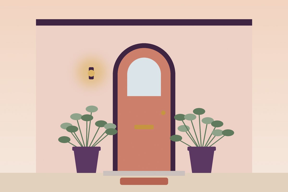 Arched front door with potted plants and a warm porch light